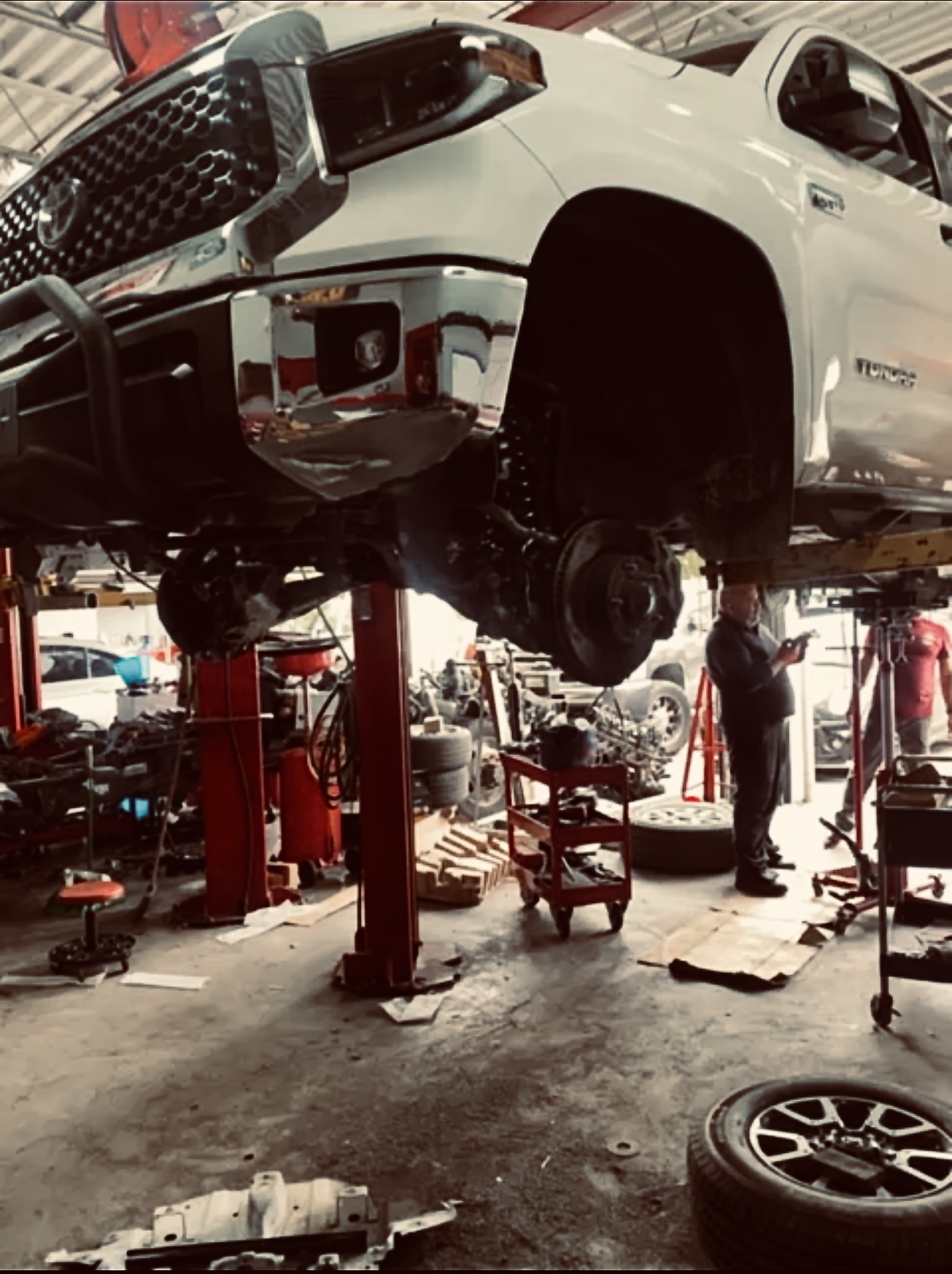Rincon's Auto Shop mechanic inspecting a vehicle on a hydraulic lift